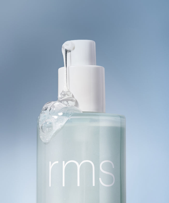 Clear gel texture dripping from the white pump of a translucent light blue bottle labeled rms, representing the Kakadu Clean Cleansing Gel with clean ingredients and sustainable packaging.
