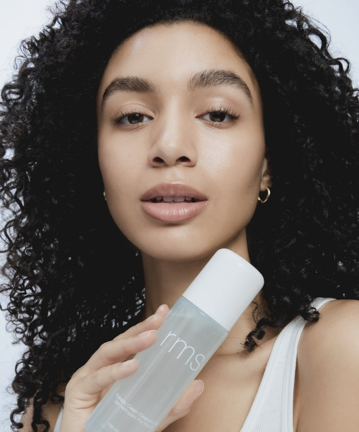 Young woman with natural makeup holding a bottle of Kakadu Clean Cleansing Gel, showcasing clean beauty and skincare with natural ingredients in recyclable packaging.