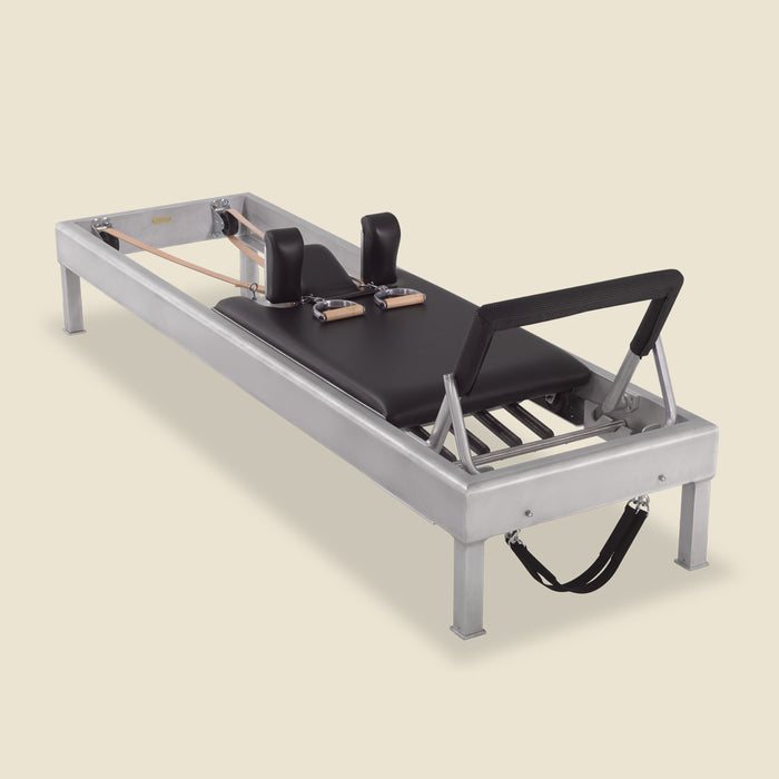 Padded black foot bar cover fitted on an aluminum Pilates reformer, top view.