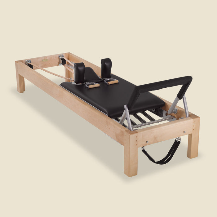 Padded black foot bar cover attached to the foot bar of a wood Pilates reformer.